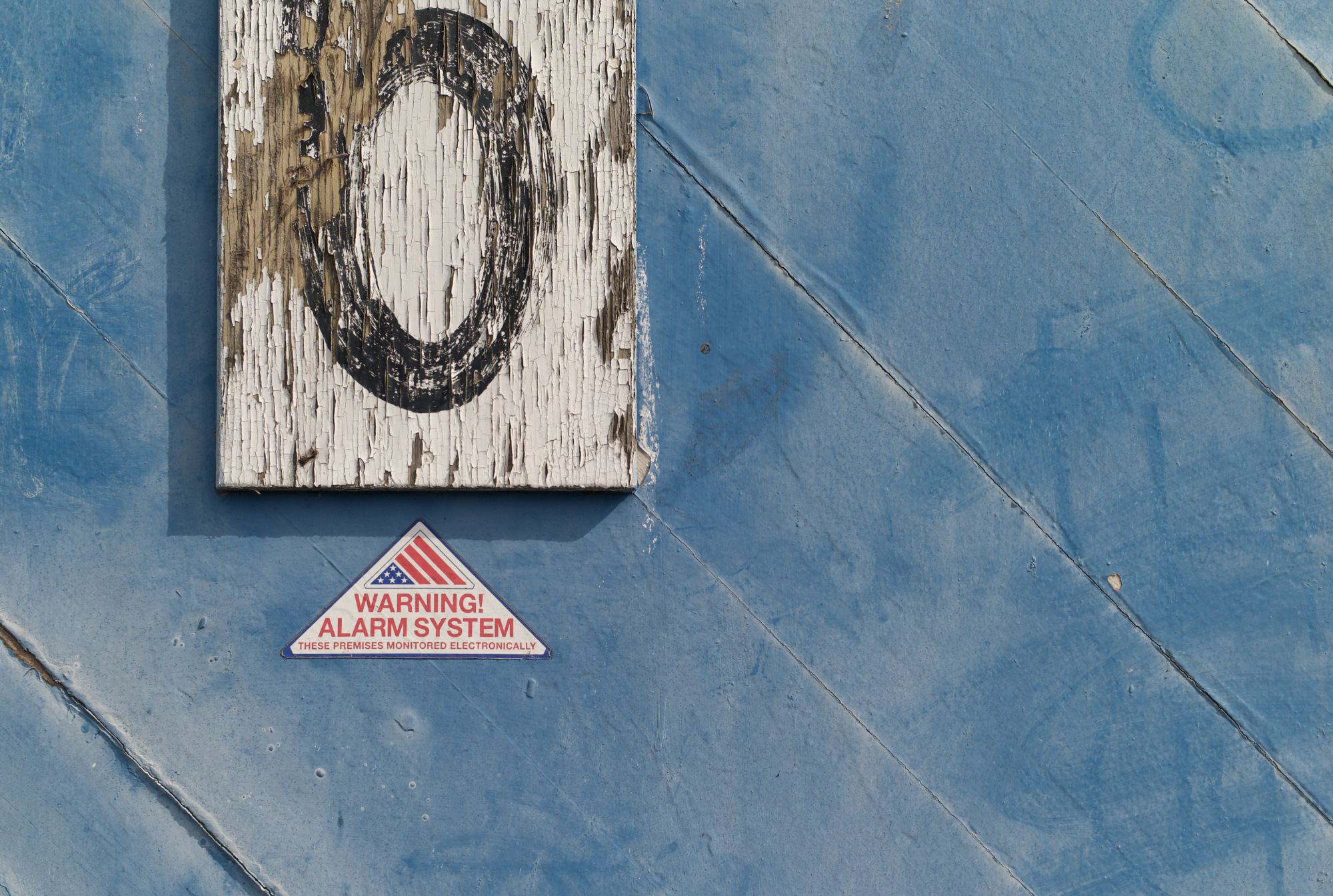 A mysterious photo showing a weathered sign with a zero above a triangular sign reading "Warning Alarm System"